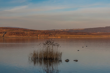 Milada lake in winter cold orange evening in north Bohemia