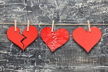 Broken / stitched / healthy hearts hanging on rope. Valentine's Day background