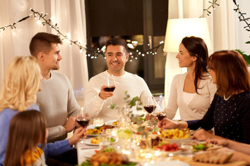 celebration, holidays and people concept - happy family having dinner party, drinking red wine and toasting at home
