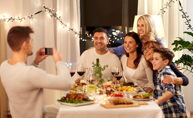 celebration, holidays and people concept - happy family having dinner party at home and taking selfie by smartphone