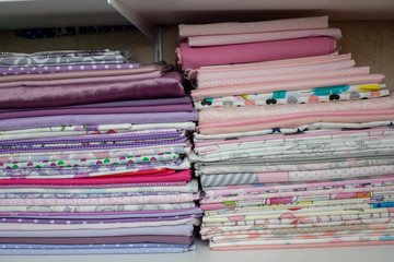 lots of bundles of different verities of new fabric in many color collections kept on the shelf of a local store in Asia