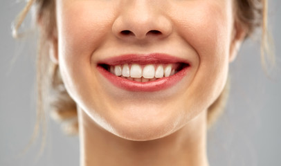 oral care, dental hygiene and people concept - close up of smiling woman face with white teeth over...