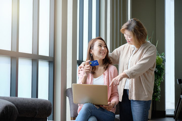 Mother hugging and teasing with her daughter while shopping online, happy family concept.