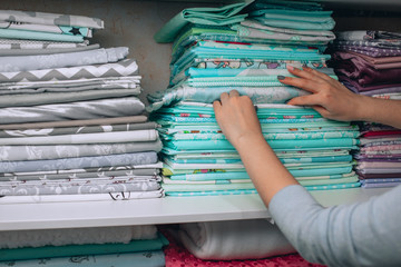 lots of bundles of different varieties of new fabric in many color collections kept on the shelf of a local store in Asia