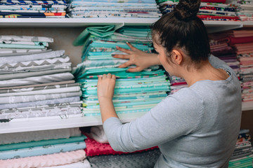 lots of bundles of different varieties of new fabric in many color collections kept on the shelf of a local store in Asia