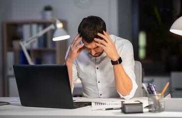 business, deadline and stress concept - businessman with papers working at night office