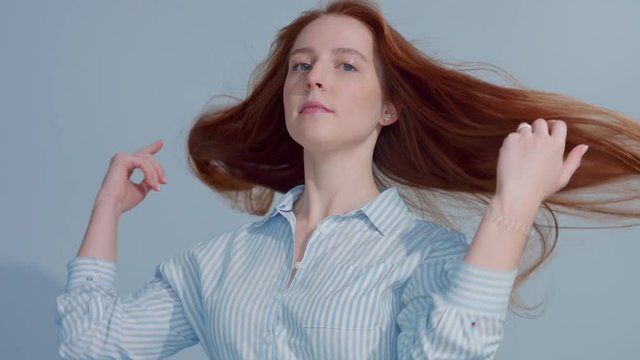 gingerhead red hair, ginger hair model with blue big eyes in studio with blowing hair in slow motion from 60fps. Beauty straight shiny hair blowing,