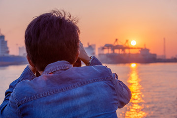 Fototapeta premium Male photographer taking photo of riverside sunset.