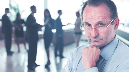 Portrait of a businessman psychologist - consultant on the background large team working