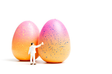 Miniature people  painting Easter-eggs for Easter day on white background 