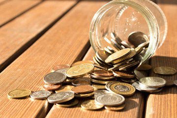 Various coins are scattered on a wooden table. The concept of poverty