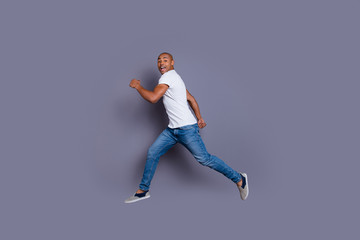 Fototapeta na wymiar Full length body size profile side view portrait of his he nice handsome attractive masculine cheerful guy in white shirt jeans having fun running away isolated over gray pastel background