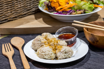 Dimsum with soy sauce asian cruisine traditional food with fork and spoon wooden, chopstick and colorfull vegetable on background.