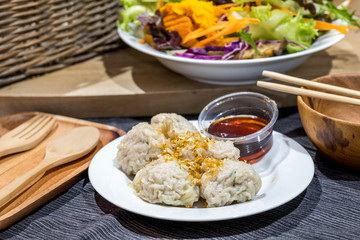 Dimsum with soy sauce asian cruisine traditional food with fork and spoon wooden, chopstick and colorfull vegetable on background.