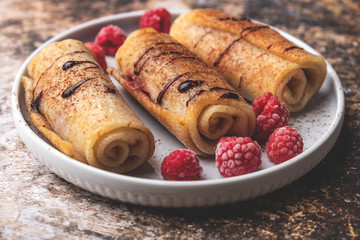 Delicious homemade crepes with raspberries and chocolate syrup, copy space