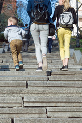 Many walking legs. Legs of children and mothers climb the stairs in the summer.