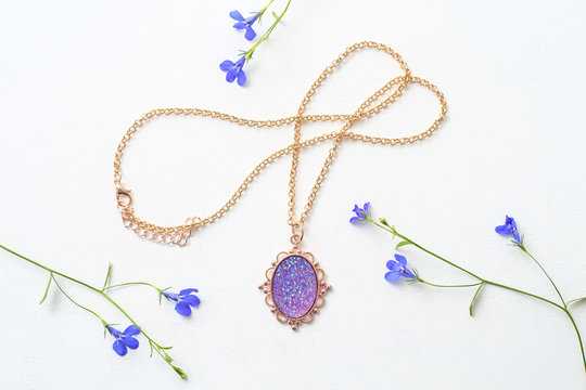 Beautiful female pendant on a chain, decoration for girls on white background, purple stone in gold frame