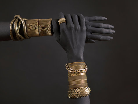 Black woman's hands with gold jewelry. Oriental Bracelets on a black painted hand.