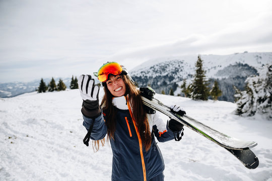 Portrait of beautiful woman with ski and ski suit in winter mountain