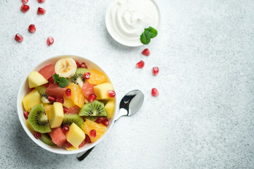 Tropical fruit salad in a white plate with sauce on a light background top view copy space