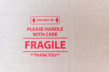 closeup view of cardboard packaging surface with red printed text This way up please handle with care fragile thank you