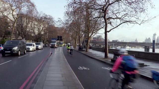 Cyclists Ride In A Busy Cycle Lane In London By The Thames Next To Road Traffic