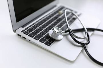 Stethoscope lying on a laptop keyboard in a concept of online m