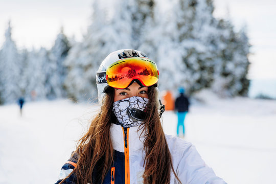 Ski, skier, sun and winter fun - woman enjoying ski vacation. Sport, leisure and people concept - happy young woman in ski goggles outdoors. Ski resort - Image