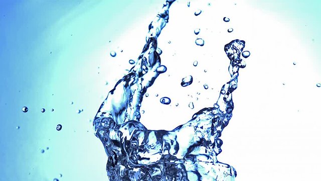 Water splashing from Glass against Blue Background, Slow Motion