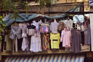 Clothes of different colors weigh on hangers at a street shop, open second-hand showcase