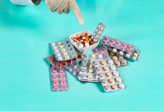Close up of young woman's hands taking pills from a colorful pile on the table
