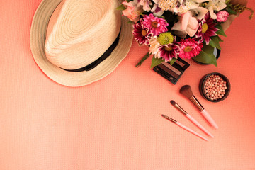 Fashion woman look spring and summer flat lay on coral color with bright flowers, accessories, cosmetic in color copy space