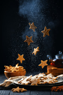 Falling stars shaped cookies with powdered sugar. Vertical composition on a dark background