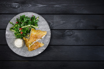 Strudel with chicken, zucchini and vegetable salad, served on the ceramic plate.