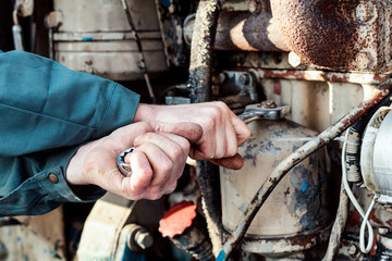 Farmer mechanic repairing tractor. Male hand holding wrench, repairing tractor engine.