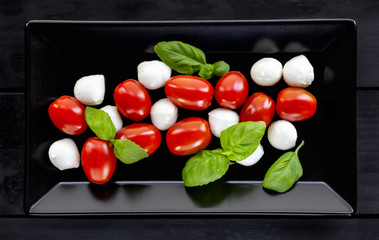 Healthy caprese salad in plate on  white wooden background