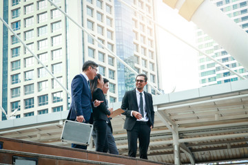 Asian office workers wearing a suit stand talking about doing business investment.