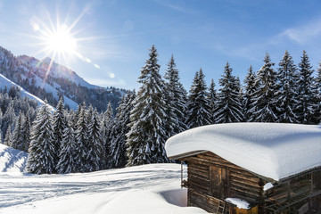 Schneebedeckte Hütte am Berg im Winter unter blauem Himmel
