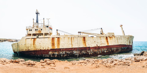 Fototapeta premium Old damaged rusty transportation ship after crash on the coastline.