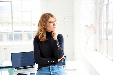 Portrait of casual businesswoman deep in thought while standing in the office