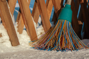 A plastic broom with multicolored bristles of the pile stands in the snow. The concept of cleaning ...
