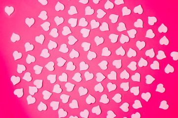 Beautiful bright pink background with small hearts, top view. The concept of Valentine Day.