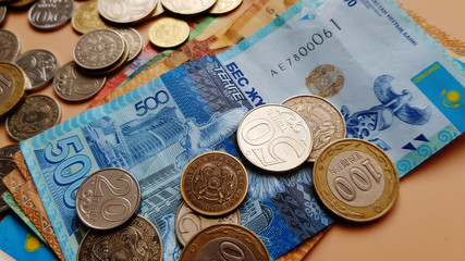 Tenge. Money. Kazakh coins and bills are on the beige table close-up..
