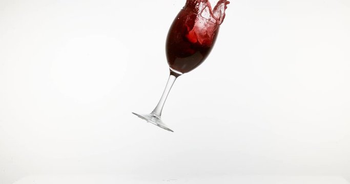 Glass of Red Wine Falling and Splashing against White Background, Slow motion 4K