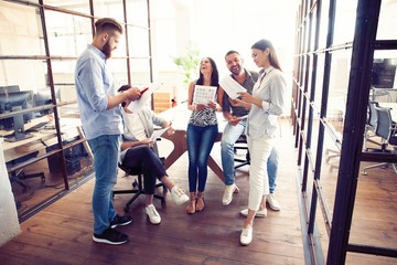 Sharing fresh ideas. Group of young business people in smart casual wear talking and smiling in the office hallway.
