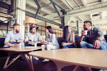 Successful young business people are talking and smiling during the coffee break in office.