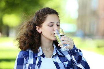 Young girl drinking water in the park