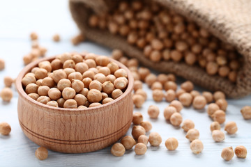 Chickpeas in bowl and sackcloth on wooden table