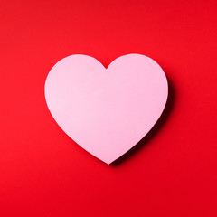 Pink heart cutted from paper over red background with copy space. Top view. Valentine's Day. Love, date, romantic concept. Square crop.