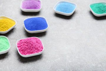 Colorful holi powder in bowls on grey background